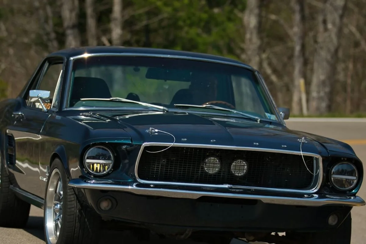 A person test driving a vintage classic car on a scenic road